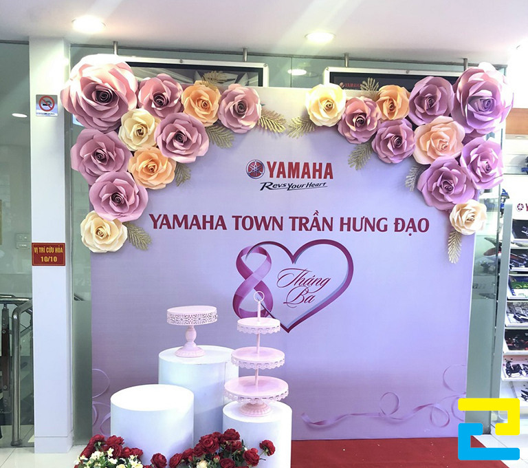 Mẫu 20: Backdrop 8/3 được trang trí viền hoa đẹp bắt mắt, có kiểu chữ đơn giản - nghệ thuật, phông nền có tông màu tím chủ đạo