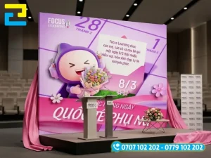 Mẫu 3: Backdrop 8-3 được thiết kế với hình ảnh nhân vật cùng thiệp tri ân, có kiểu chữ đơn giản - nghệ thuật, tông màu tím hồng