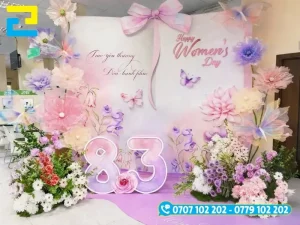Mẫu 17: Mẫu backdrop 8/3 được thiết kế đơn giản với tông màu trắng tím chủ đạo, có kiểu chữ đơn giản - nghệ thuật đẹp mắt, được trang trí hoa xung quanh