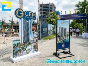 Mẫu standee 3D cắt bế bo sát theo đường viền dự án đầu tư (bên trái) và mẫu standee khung sắt chắc chịu lực chống lật do gió mạnh ngoài trời (bên phải)